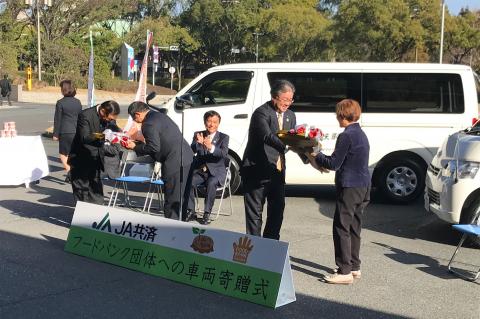 JA共済連 福岡から式典キーを受け取るフードバンク２団体の代表者